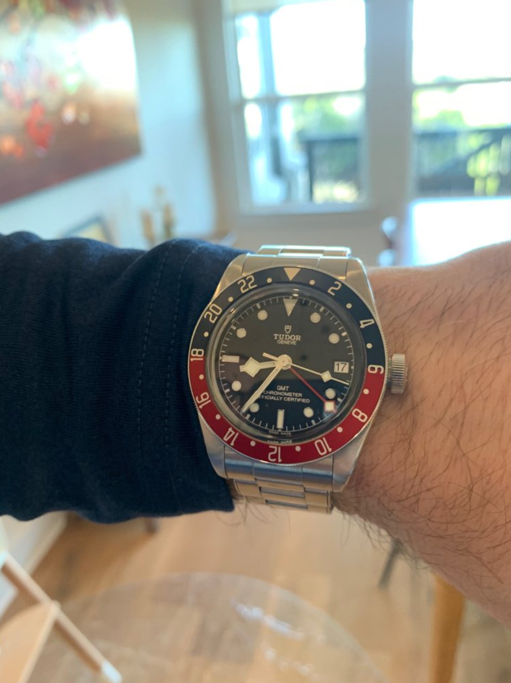 A wristwatch with a black face, red and blue bezel, and stainless steel band.